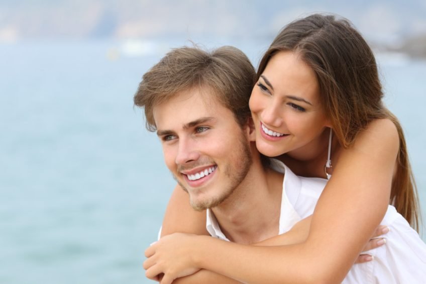 Happy couple in love looking away with perfect smile on the beach